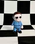 Toy figure of a character in a blue outfit on a black and white checkered background