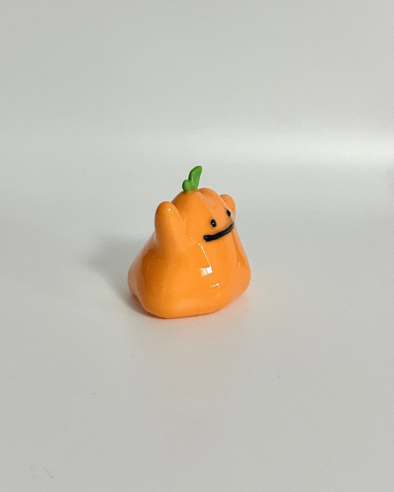 Small orange figurine with a face on a white surface
