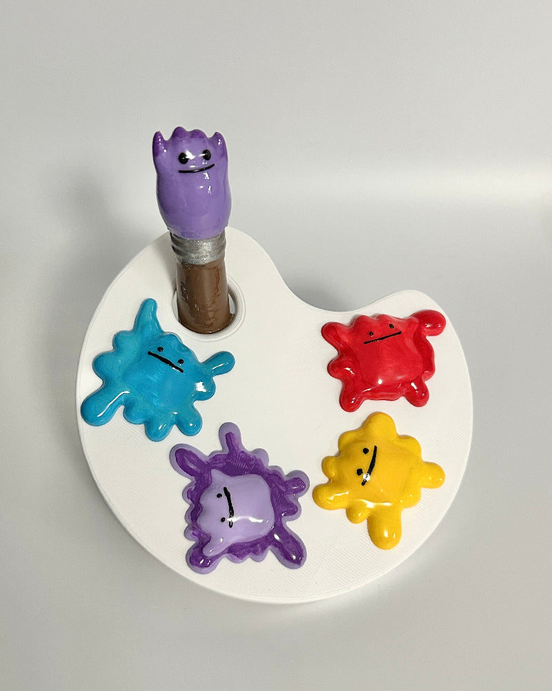 Colorful monster-themed paint palette with a brush on a white background