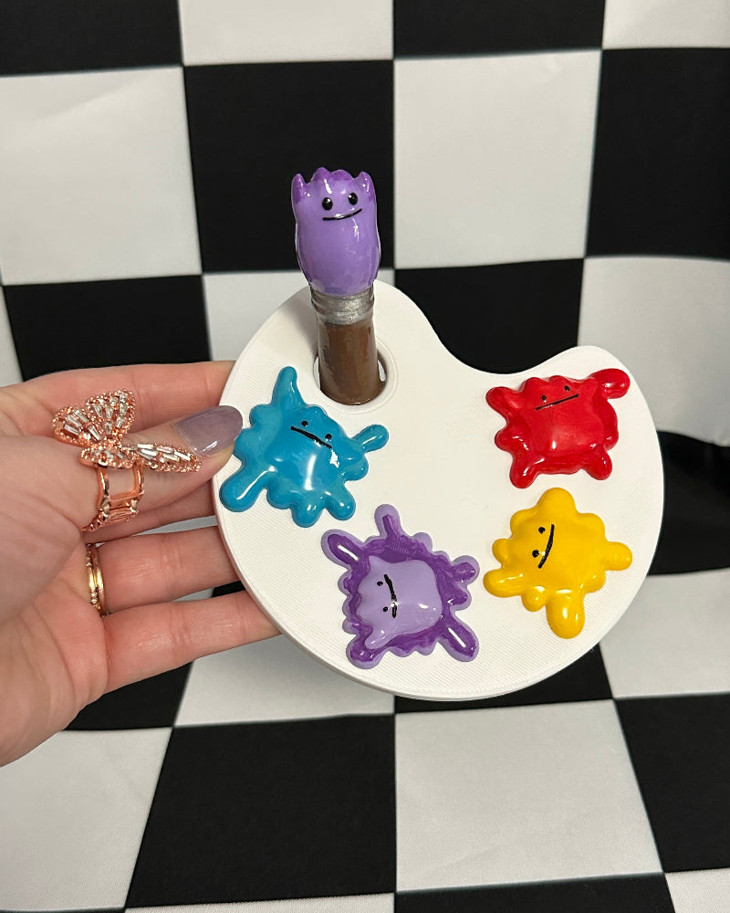 Colorful paint palette with a hand holding it against a checkered background