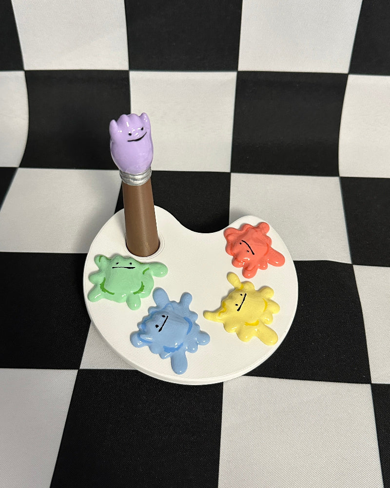 Colorful paint palette with a purple handle on a checkered background