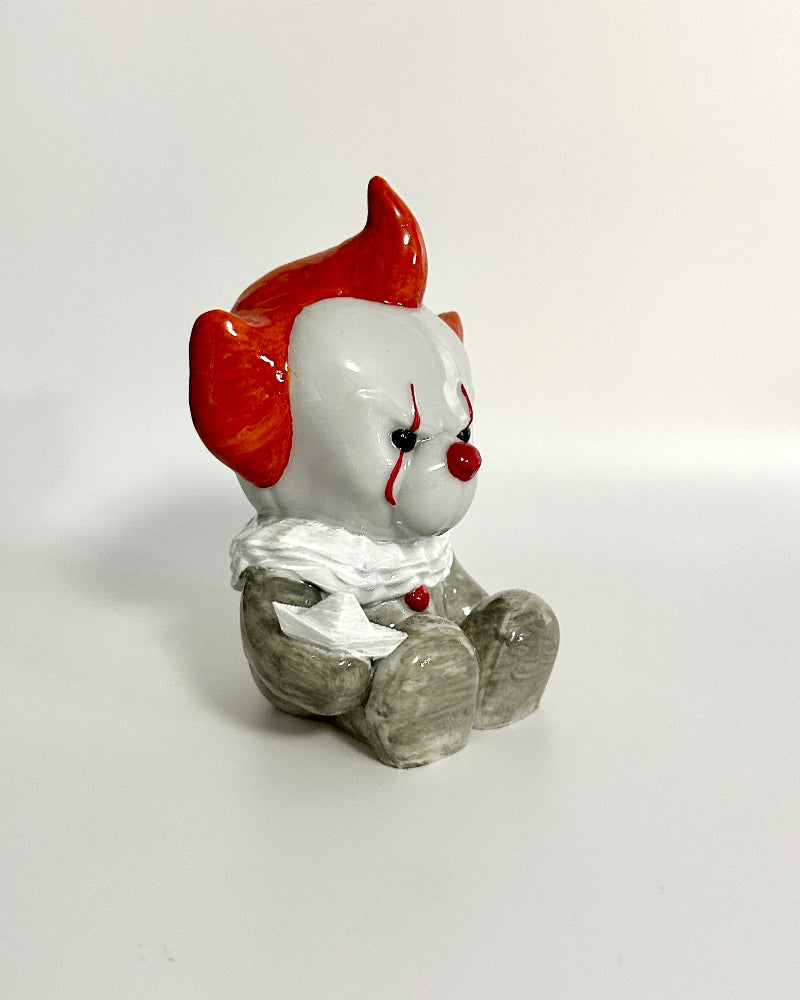 Small figurine of a clown with red hair and white face on a white surface