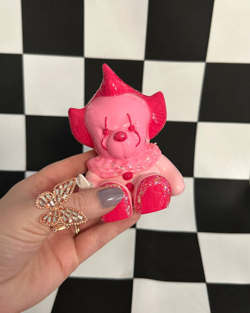 Pink pig figurine held by a hand on a black and white checkered background