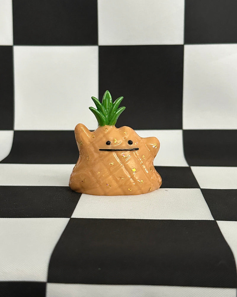 Star-shaped object with a pineapple on top on a black and white checkered background