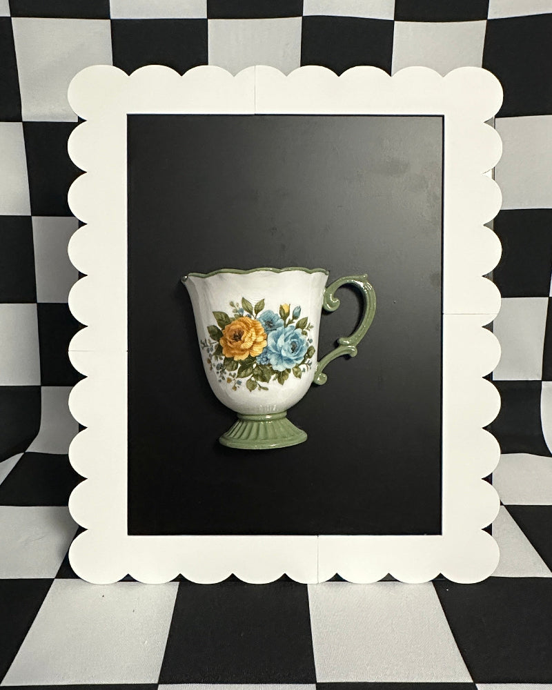 Decorative teacup with floral design in a white frame against a black and white checkered background
