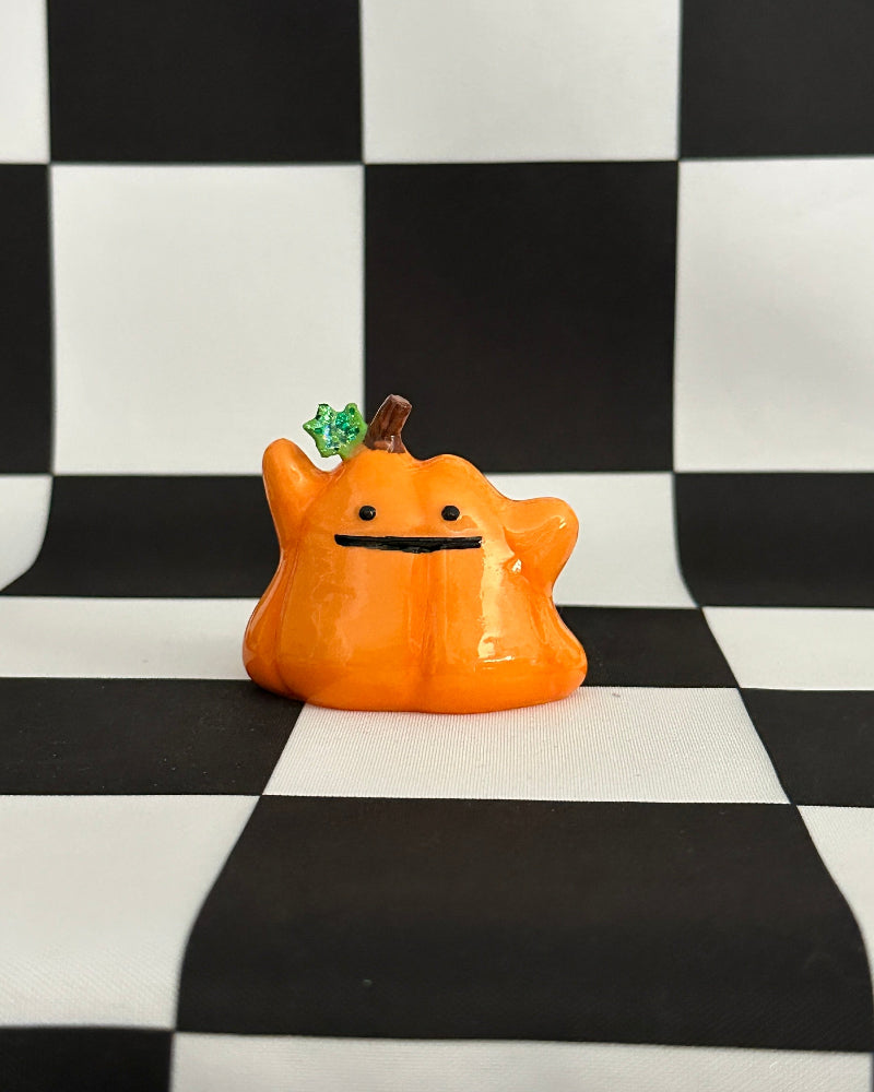 Orange creature figurine with a black checkered background