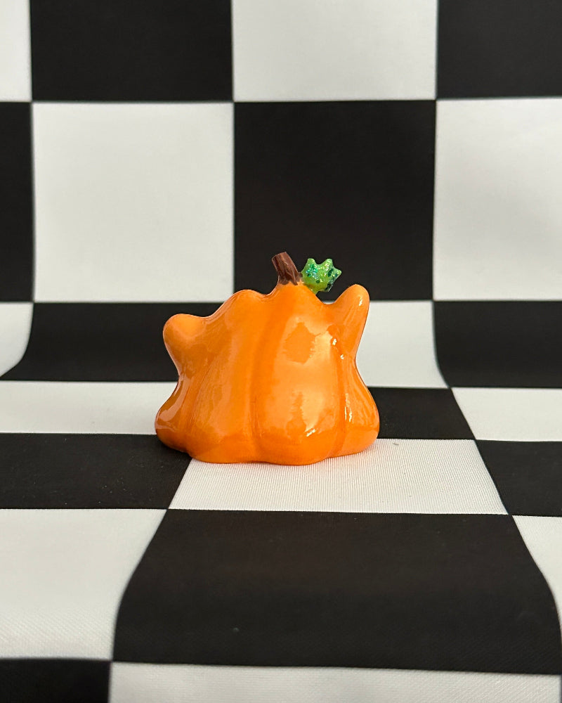 Orange ceramic pumpkin on a black and white checkered background