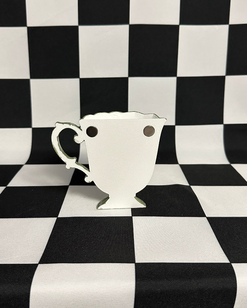 teacup magnet with black spots on a black and white checkered background