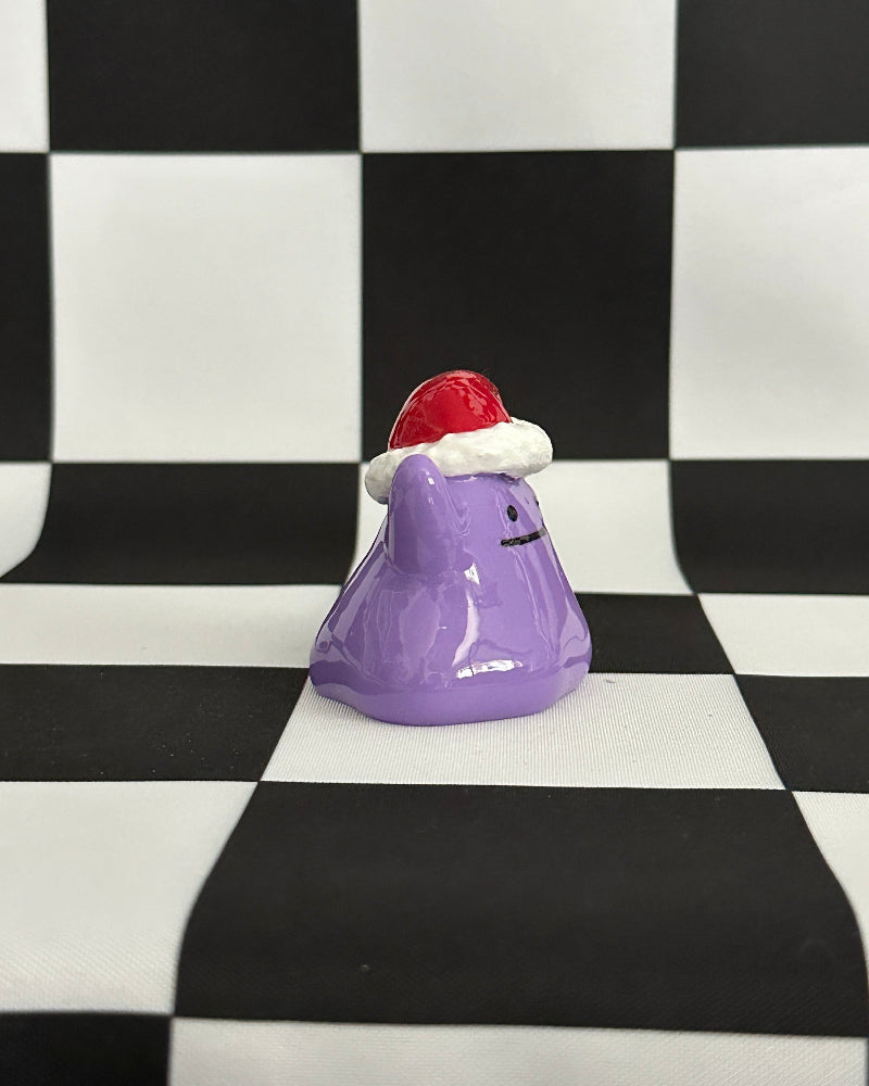 Purple character figurine with a red hat on a black and white checkered background