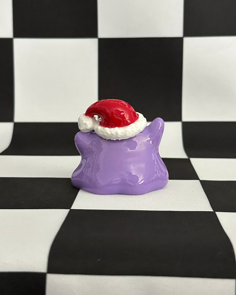 Purple star-shaped object with a Santa hat on a black and white checkered background