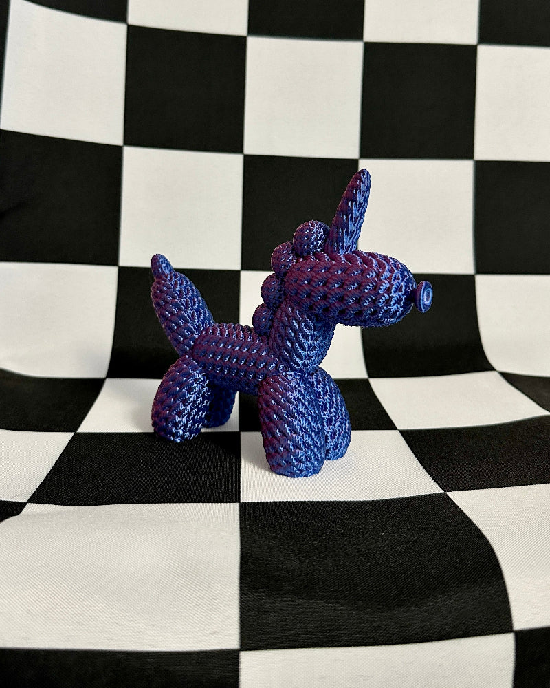Blue balloon dog sculpture on a black and white checkered background