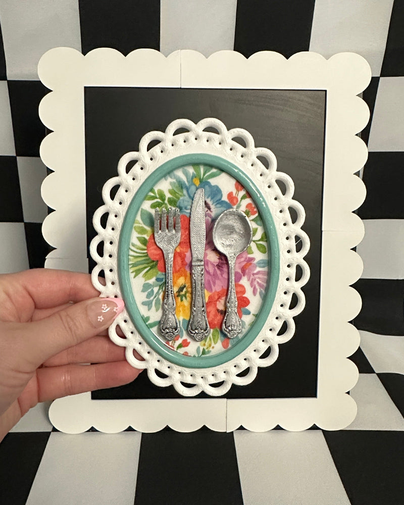 Decorative card with cutlery design held against a black and white checkered background