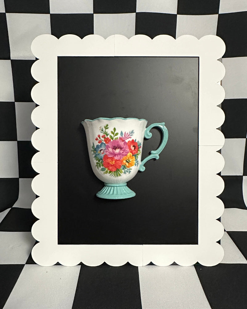 Decorative teacup with floral design in a white frame on a black and white checkered background