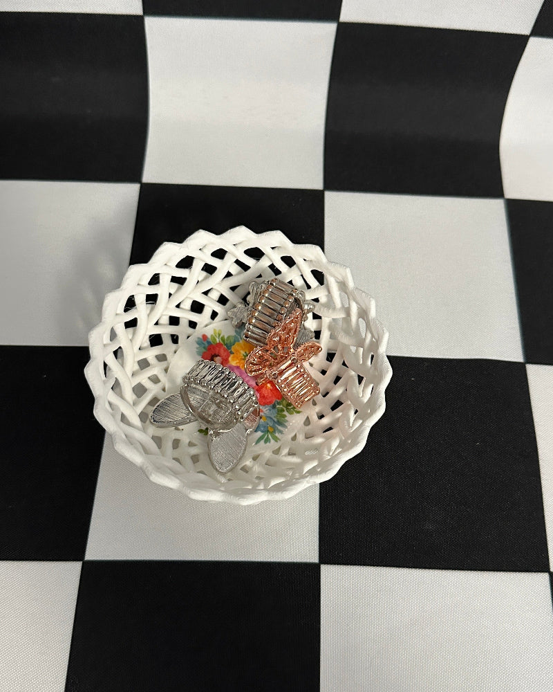 Decorative butterfly figurines in a white lace doily on a black and white checkered background