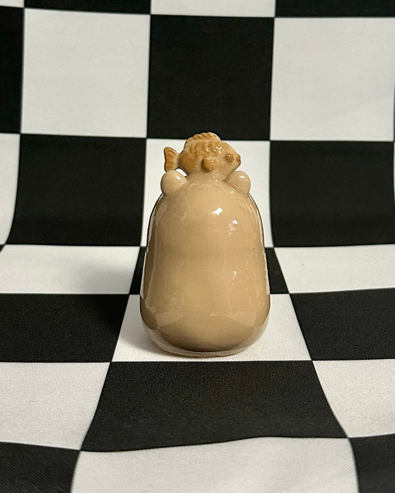 Beige ceramic object on a black and white checkered background