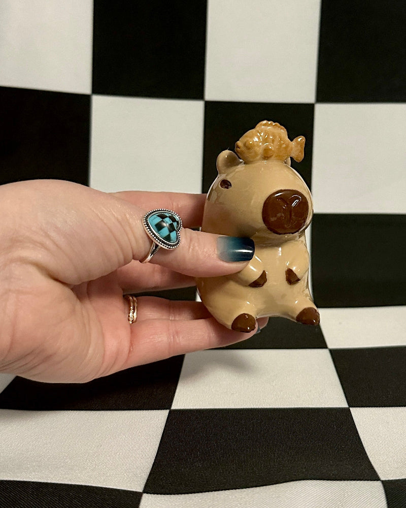 Hand holding a small figurine against a black and white checkered background
