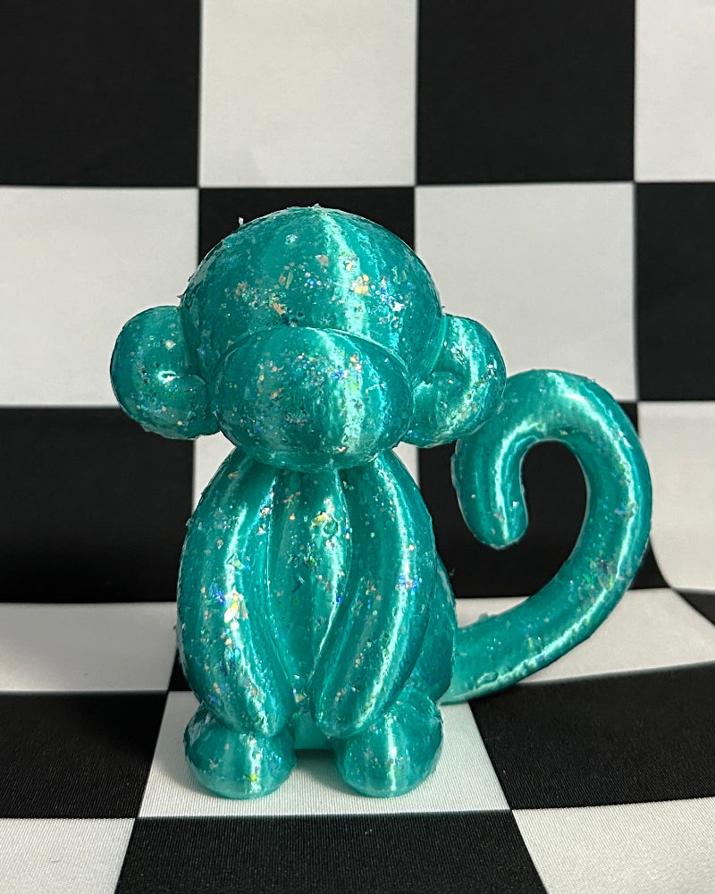 Turquoise monkey figurine on a black and white checkered background