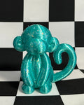 Turquoise monkey figurine on a black and white checkered background