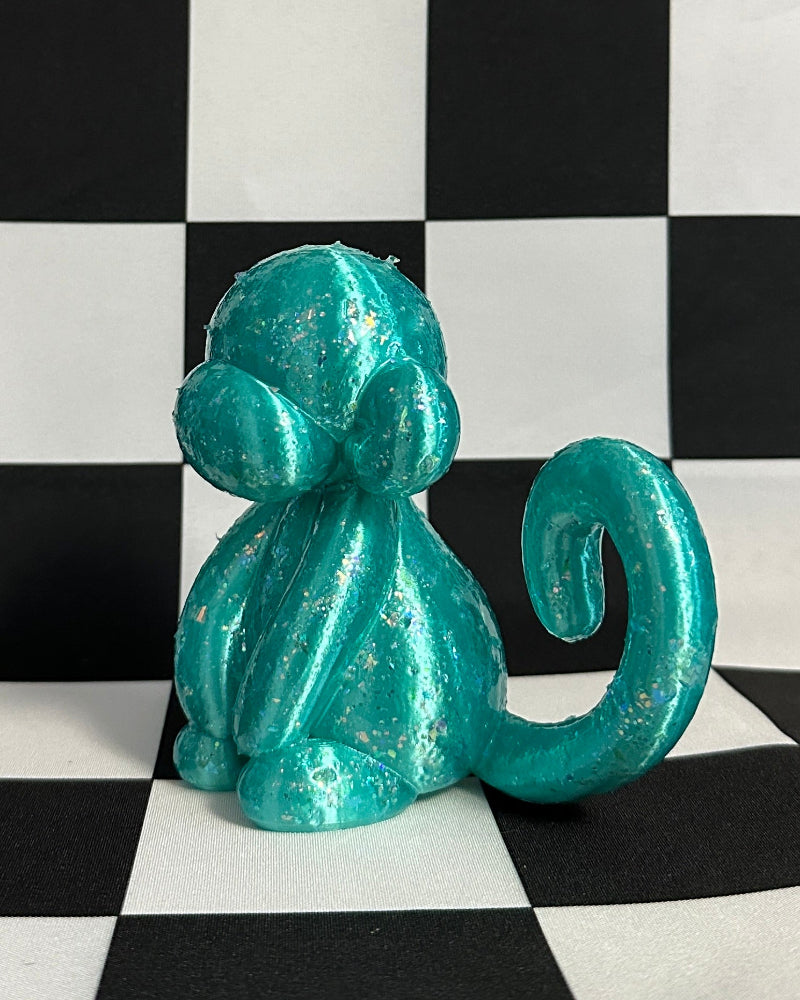 Turquoise monkey figurine on a black and white checkered background