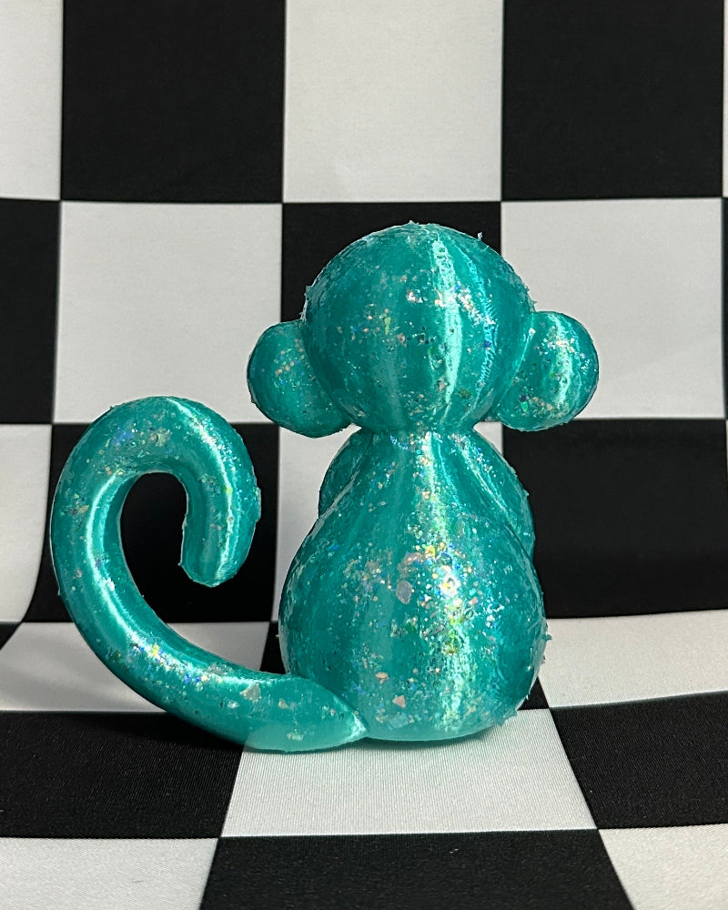 Teal monkey figurine on a black and white checkered background