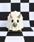 A small white ceramic dinosaur figurine with green accents and beige horns, standing on a black and white checkered surface.