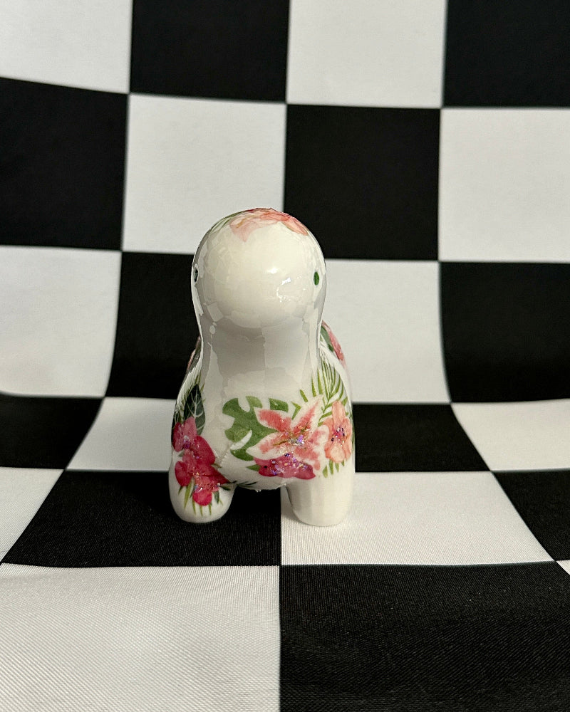Small ceramic figurine with floral design on a black and white checkered background