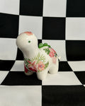 Decorative ceramic dinosaur figurine with floral patterns on a black and white checkered background