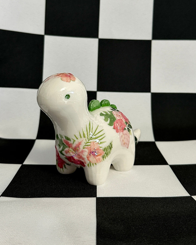 Decorative ceramic dinosaur figurine with floral patterns on a black and white checkered background
