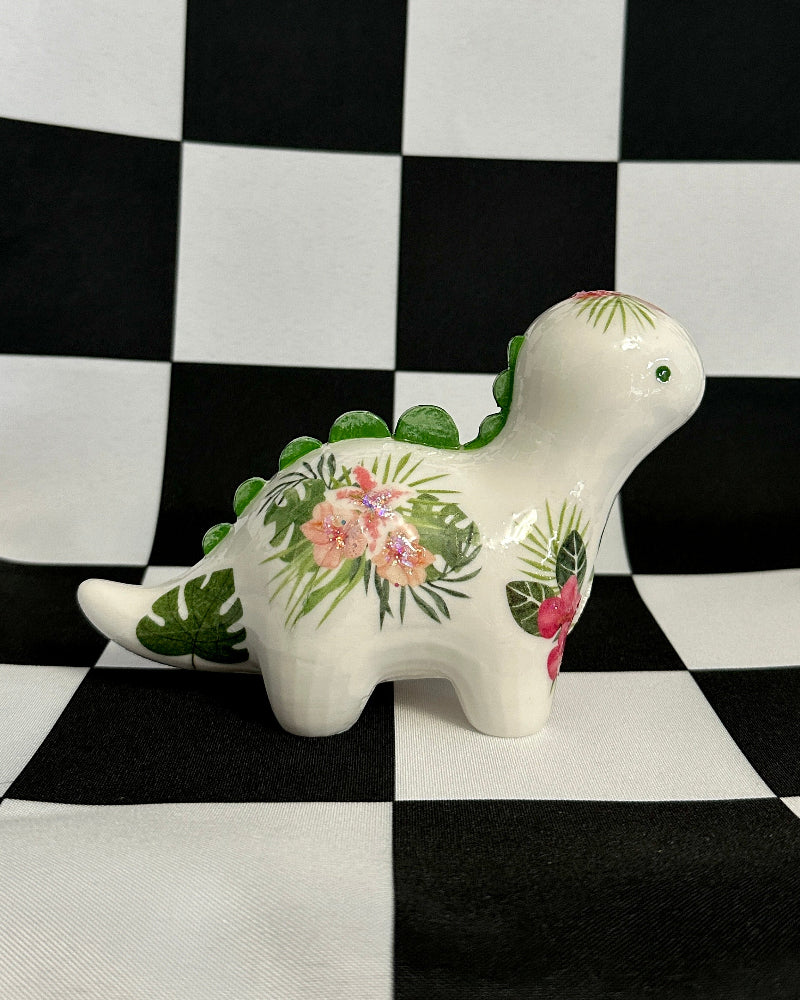 Decorative dinosaur figurine with floral design on a black and white checkered background
