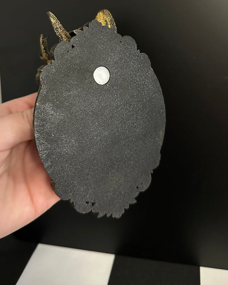 Black textured object with a white circular detail held against a black and white checkered background