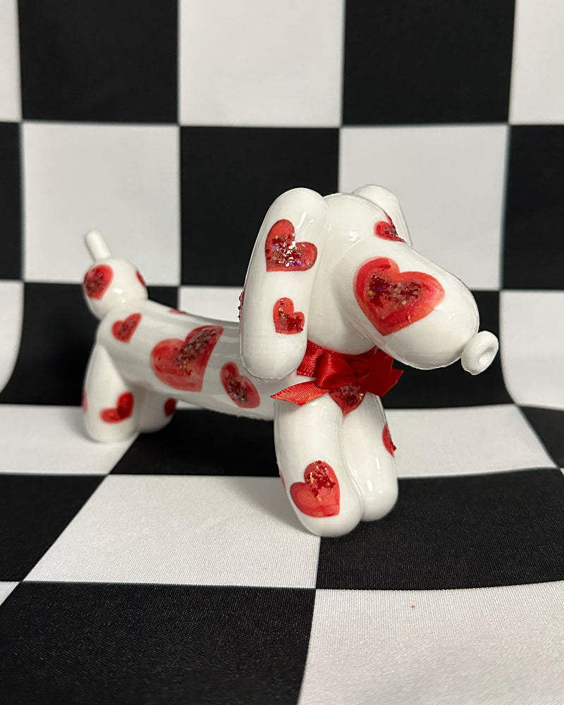 White dog figurine with red heart patterns on a black and white checkered background