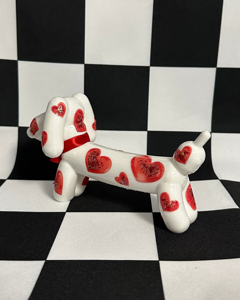 Small dog figurine with red heart patterns on a black and white checkered background