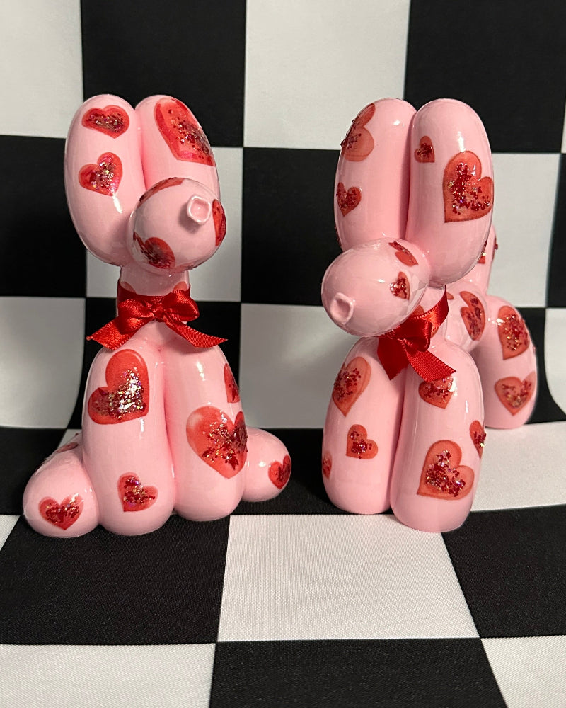 Pink dog-shaped candles with red bows on a checkered background