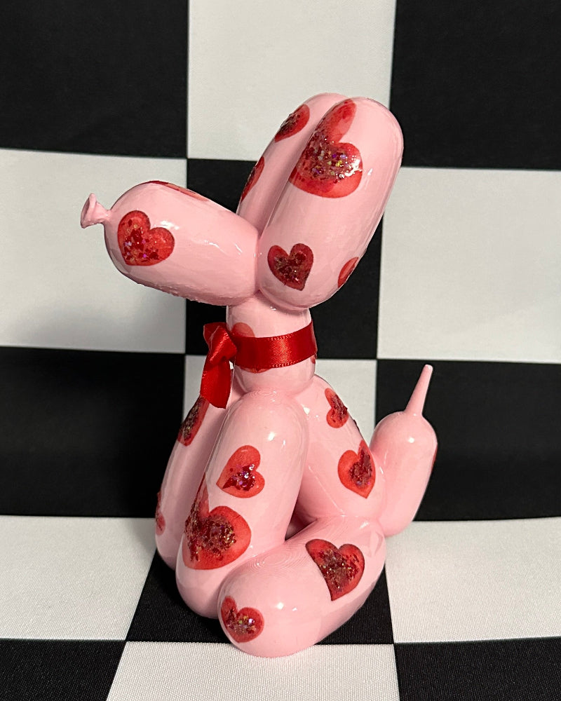 Pink dog figurine with heart patterns on a black and white checkered background