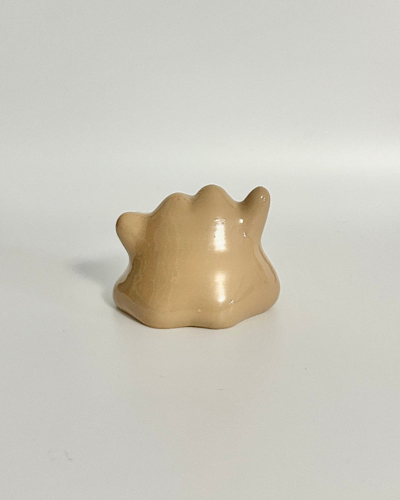 Small beige ceramic animal figurine on a white surface with a neutral background