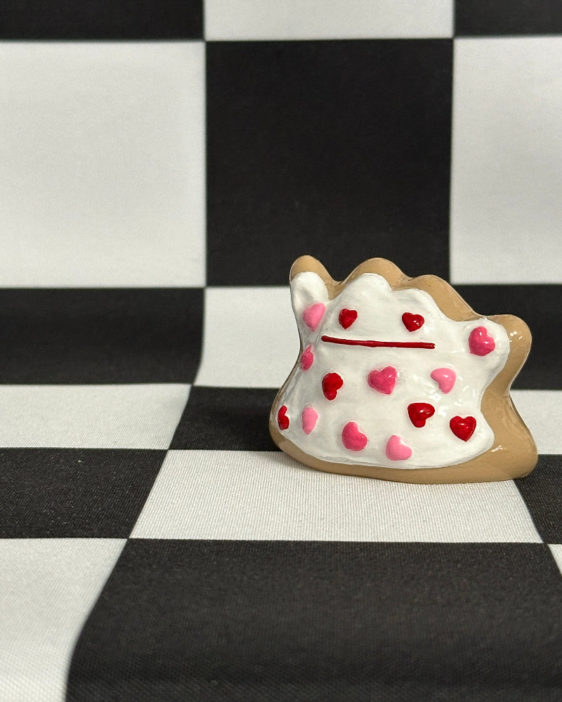 Decorative cookie-shaped container with heart designs on a black and white checkered background
