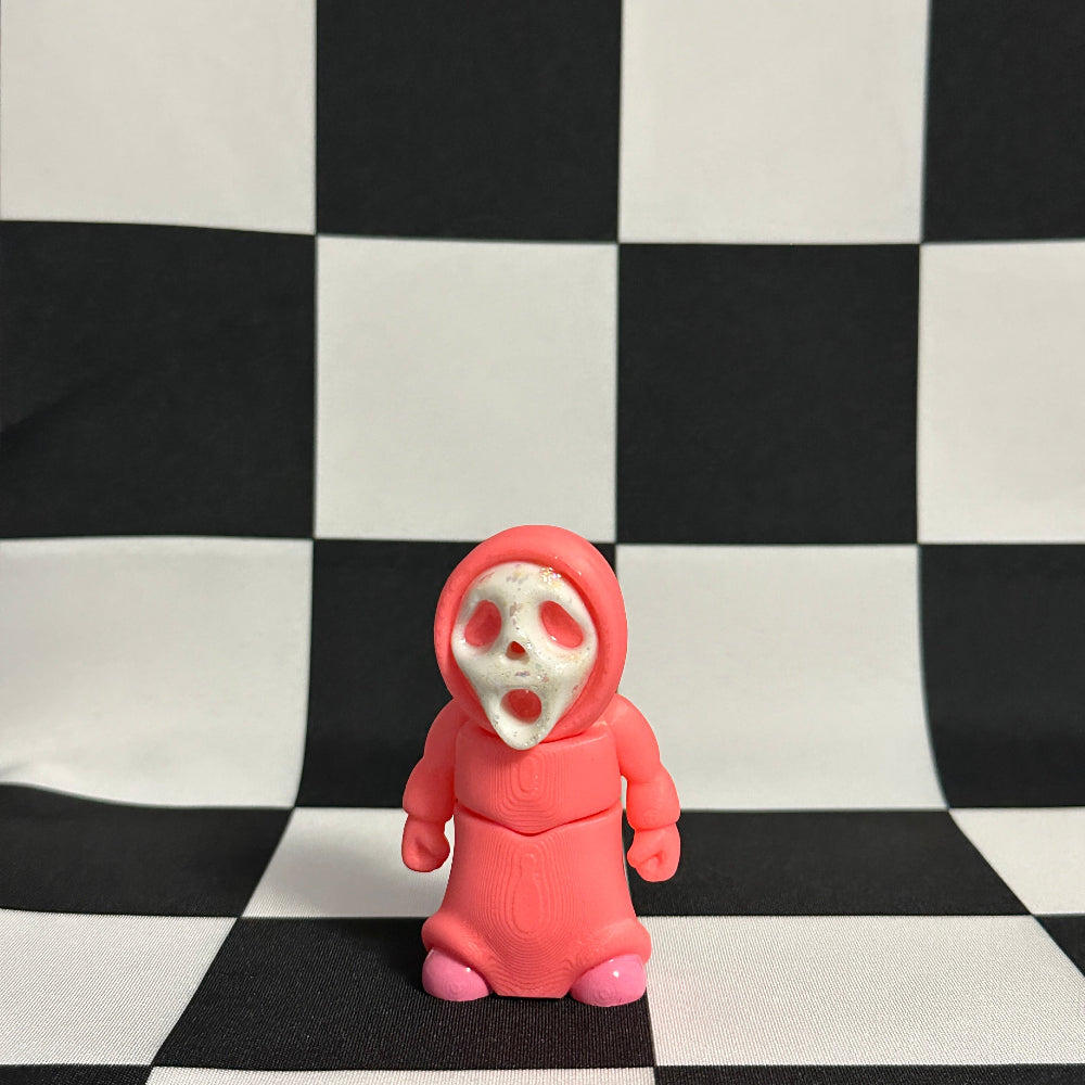 Pink toy figure with skull face on a black and white checkered background