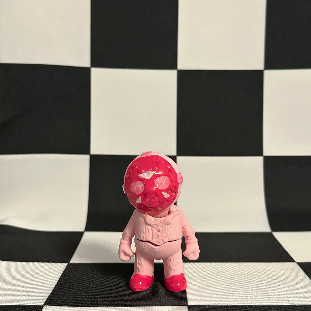 Pink toy figure with a red head on a black and white checkered background