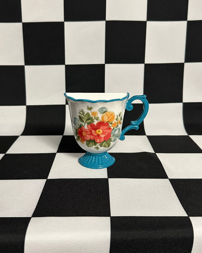 Decorative mug with floral design on a black and white checkered background