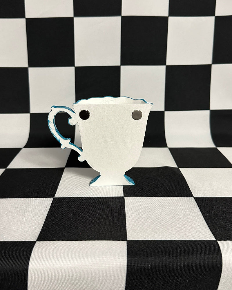 White ceramic cup with blue interior on a black and white checkered background