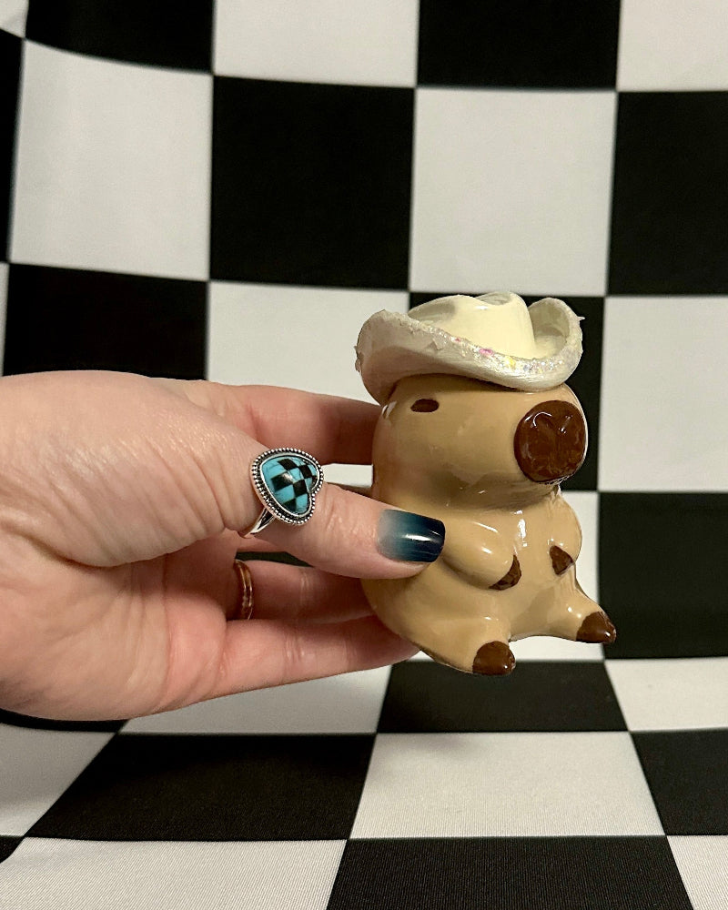 Hand holding a small figurine against a black and white checkered background