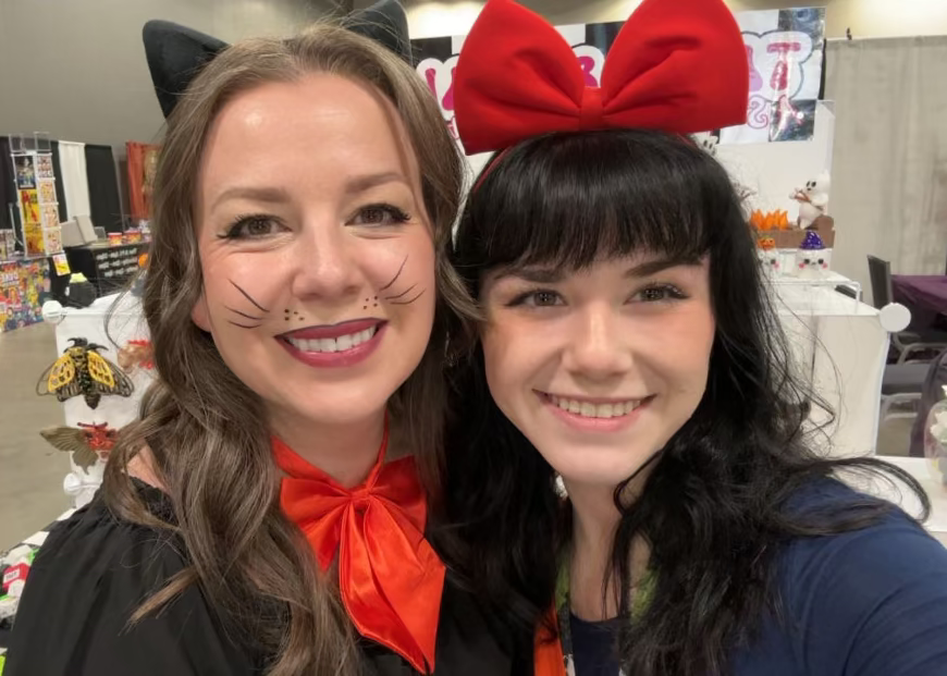Two people wearing Halloween costumes with a festive background.